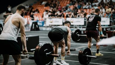 A group of athletes performing deadlifts during a competitive weightlifting event indoors.