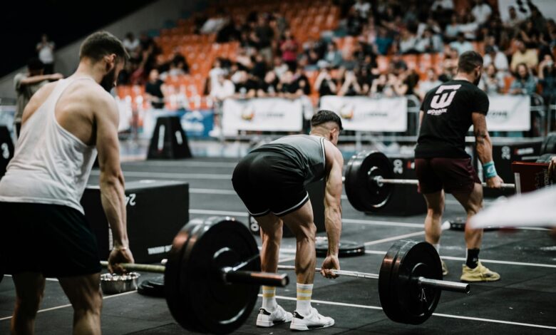 A group of athletes performing deadlifts during a competitive weightlifting event indoors.