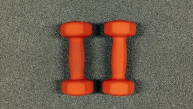 A close-up image of orange dumbbells on a textured gray surface, ideal for fitness themes.