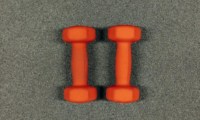 A close-up image of orange dumbbells on a textured gray surface, ideal for fitness themes.