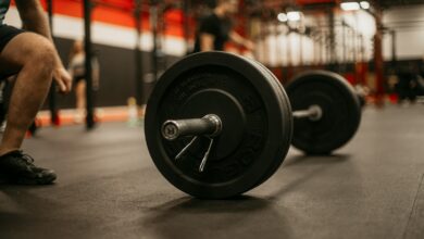 a man squatting down next to a barbell in a gym