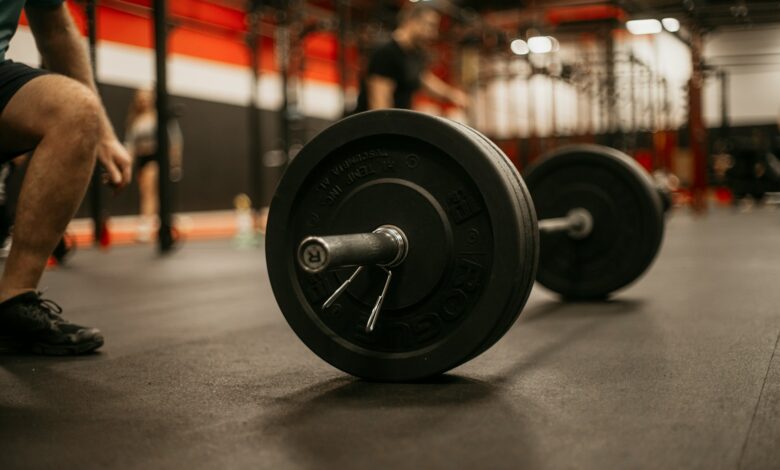 a man squatting down next to a barbell in a gym